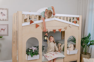 Children playing on a wooden playhouse bed in a room with plants and decor.