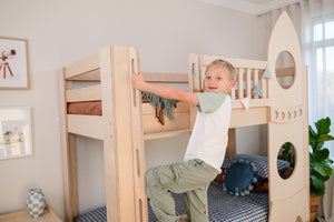 Child playing on a wooden bunk bed in a child-friendly room.